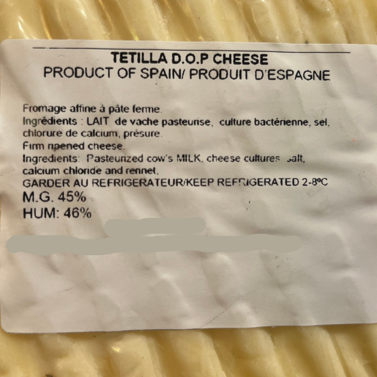 A round wedge of Tetilla D.O.P. Cheese with a white product label showing production details.