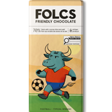 A bar of FOLCS Friendly Chocolate featuring a colorful illustration of a bull soccer player on a field. The packaging is cream and beige with a white top section containing the brand name 'FOLCS' and product details.