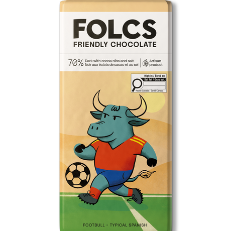 A bar of FOLCS Friendly Chocolate featuring a colorful illustration of a bull soccer player on a field. The packaging is cream and beige with a white top section containing the brand name 'FOLCS' and product details.